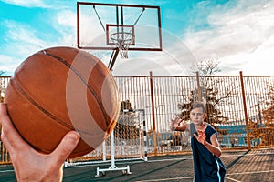 Sports and basketball. A man`s hand holds a basketball for submission. In the background, a teenager preparing to catch a ball.