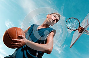 Sports and basketball. A young teenager in a black tracksuit stands with a ball in his hands and prepares to throw the ball into