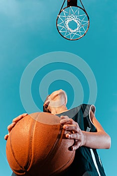 Sports and basketball. A young teenager in a black tracksuit stands with a ball in his hands and prepares to throw the ball into