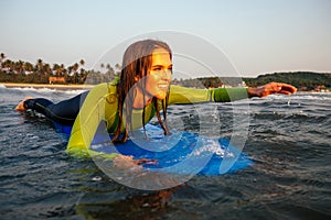 Sports beautiful woman in a diving suit lying on a surfboard waiting for a big wave .surf girl in a wetsuit surfing in