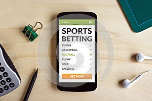 Sports betting concept on smart phone screen on wooden desk