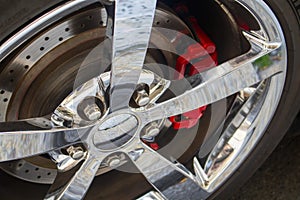 Sports car chrome wheel rim with disc brakes and red break pad