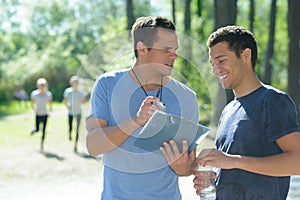sports coach showing stopwatch to male athlete