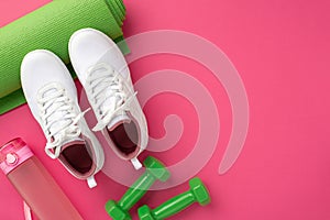 Sports concept. Top view photo of green yoga mat dumbbells pink bottle and white sports footwear on isolated pink background with