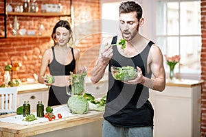 Sports couple eating healthy vegetarian food on the kitchen