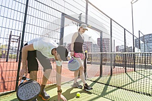 Sports couple with padel rackets posing on tennis court