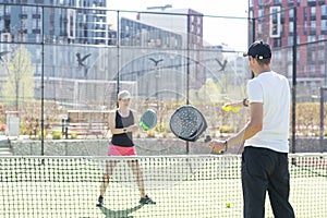 Sports couple with padel rackets posing on tennis court