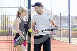 Sports couple with padel rackets posing on tennis court