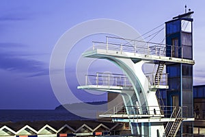 Sports diving board lit by a powerful searchlights on the outdoor pool on a dark night sky background