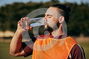 Sports, drinking water and man in field to rest after training, workout and exercise outdoors. Fitness, health and male