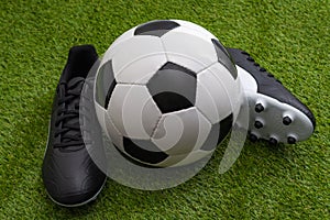 Sports equipment, athletics competition and sporting event concept with soccer ball, leather cleats or football boots on green