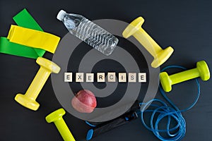 Sports equipment on black background for exercising at home. Word EXERCISE. Copy space