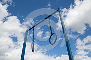 Sports equipment crossbar with two rings on the background of a forest of clouds of blue sky