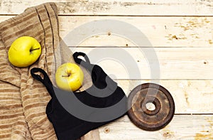 Sports equipment flat lay, old metal dumbbells and yellow apples and bra. Concept healthy lifestyle, sport and diet.