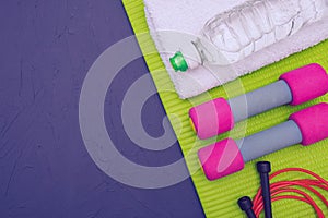 Sports equipment - green mat, bottle of water and towel, dumbbells and jump rope