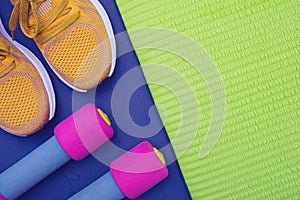 Sports equipment - green mat, yellow dumbbell sneakers, blue texture background