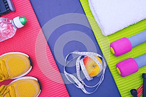 Sports equipment - mats, bottle of water and towel, sneakers and dumbbells, apple and measurement tape