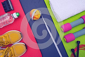 Sports equipment - mats, bottle of water and towel, sneakers and dumbbells, apple and measurement tape, lie on blue, textured