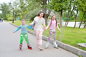 Sports family-mother with children on roller skates in the Park