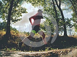 Sports figure man is running in the park alley in Sunny morning.