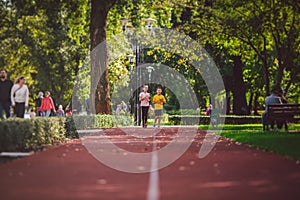 Sports and fitness in adolescence. Caucasian twins boy and girl run on the jogging track in the city park. Two children brother