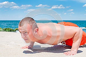 Sports. Fitness man doing push-ups on the beach