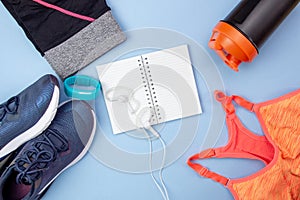 Sports flat layout. Fitness accessories sneakers, headphones, clothes, bottle, watch and an open notebook for writing