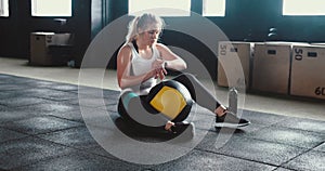 Sports gadgets. Beautiful young fit woman doing exercises with cross fit ball at gym, using smart watch mobile app.