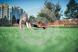 Sports girl doing morning gymnastics workout on a football field. Fitness, sport, health energy.