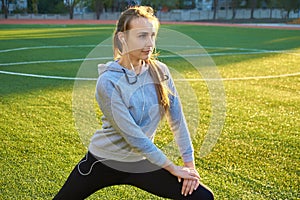 Sports girl doing morning gymnastics workout on green grass. In the control of warm sunlight. Fitness, sport, health, energy.