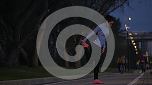 Sports girl doing stretching before training in the evening park. the sportswoman prepares for training in the open air.