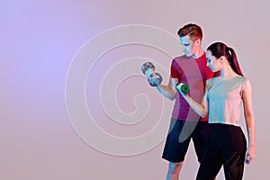 Sports girl and guy doing exercises. Keep dumbbells, train the biceps. Dark background, space for text