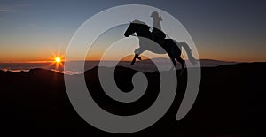 Sports girl riding a horse at countryside in a field, isolated image, black silhouette on a sunset background, against morning sky