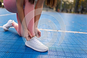 Sports girl tying laces in sneakers.