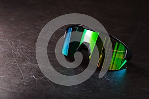 Sports glasses with a green mirrored lens and black frames on a black background