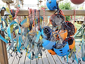 Sports helmets, carabiners, safety ropes and other safety equipment hang on a wooden crossbar