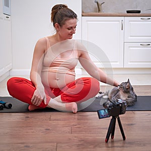 Sports at home during pregnancy and shooting videos on the camera. Pregnant woman on fitness workout leads online stream