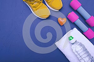 Sports at home - yellow sneakers, dumbbells and a bottle of water and a towel