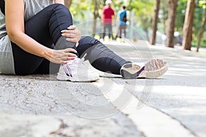 Sports injury. Woman with pain in ankle while jogging photo