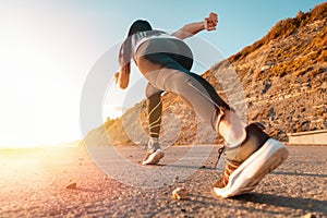 Sports and Jogging along the sea. The woman stands ready to run. In the background, the mountain and the sun. Bottom view