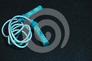 Sports Jumping rope on a black background. Blue children's jump rope on a black shiny background. Fitness concept