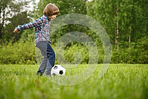 Sports Kid. Baby playing soccer ball in the park. Children play football. Family leisure