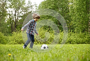 Sports Kid. Baby playing soccer ball in the park. Children play football. Family leisure