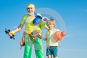 Sports for kids. Father and son sporting - family time together. Senior man and cute little boy exercising on blue sky