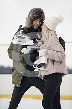 Sports and Lifestyle. Young Loving Caucasian Couple On Skatingrink With Ice Skates Posing Together Over a Snowy Winter Landscape