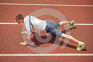 Sports man doing push-ups on running track