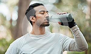 Sports, man and drinking water in park for exercise break, energy and workout rest. Thirsty athlete, asian runner and
