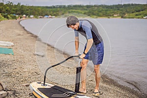 Sports man inflates pump paddle Board, fashionable modern entertainment