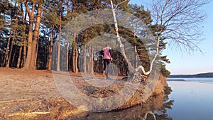 Sports man run betwen trees along lake coast. Evening workout and psychical training.