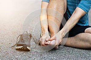 Sports man runner with injured foot while training on the asphalt road . Healthcare, medicine and people concept.